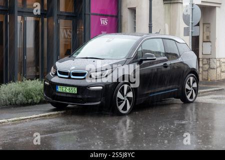 TOKAJ, UNGHERIA - 27 OTTOBRE 2023: Auto elettrica BMW i3 nera parcheggiata su strada in condizioni di forte pioggia Foto Stock