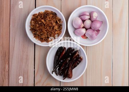 Mescolare le cipolle, i peperoncini secchi e le cipolle rosse in un piatto bianco su un pavimento di legno. Vista dall'alto Foto Stock