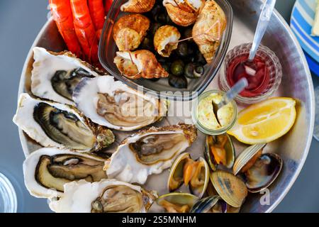 Squisito piatto di pesce con ostriche fresche, vongole, succulenti gamberi e saporito contorno di limone Foto Stock
