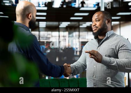 Simpatici manager aziendali che partecipano a una riunione informativa con il CEO per condividere nuove idee per la crescita dei profitti, stringendo la mano. Uomo che parla con il regista per spiegare la visione dell'evoluzione della startup, facendo stretta di mano Foto Stock