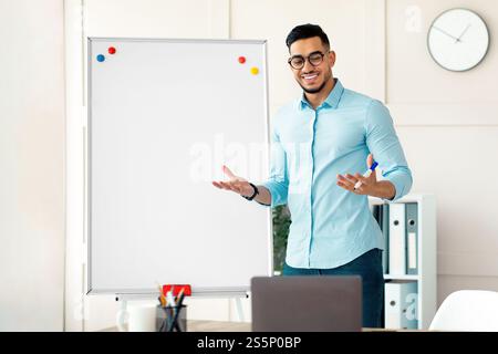 Allegro giovane insegnante arabo in piedi vicino a lavagna e spiegare la grammatica inglese agli studenti online da casa Foto Stock