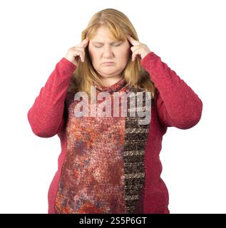 Una donna di mezza età appare stressata, tenendo i templi con le dita e chiudendo gli occhi. Sta indossando un maglione a motivi rossi Foto Stock