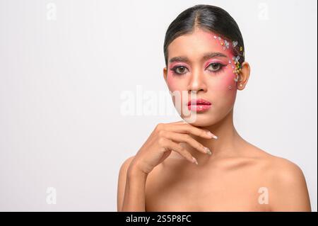 Donna che indossa trucco e decorazioni rosa sul viso. Isolato su sfondo bianco Foto Stock