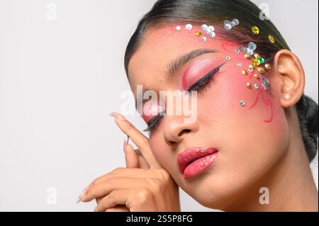 Donna che indossa trucco e decorazioni rosa sul viso. Isolato su sfondo bianco Foto Stock