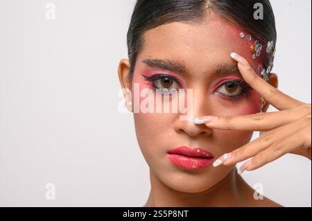 Donna che indossa trucco e decorazioni rosa sul viso. Isolato su sfondo bianco Foto Stock