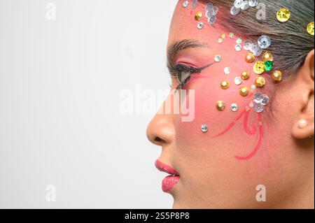 Donna che indossa trucco e decorazioni rosa sul viso. Isolato su sfondo bianco Foto Stock