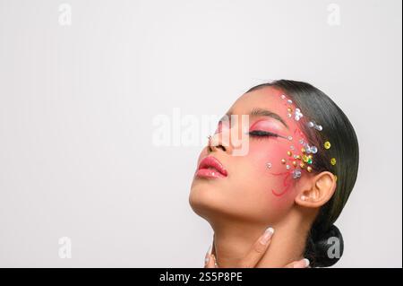 Donna che indossa trucco e decorazioni rosa sul viso. Isolato su sfondo bianco Foto Stock