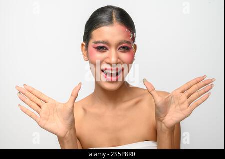 Donna che indossa trucco e decorazioni rosa sul viso. Isolato su sfondo bianco Foto Stock