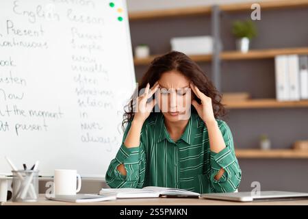 Annoiato e stanco insegnante toccare templi che soffrono di mal di testa Foto Stock
