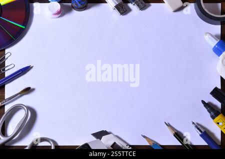 A scuola o in ufficio ancora in vita con un bianco foglio di carta bianco e molte delle forniture per ufficio. La scuola fornisce giacciono su di un legno marrone dello sfondo. Luogo Foto Stock