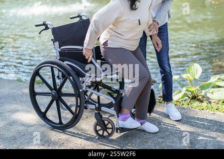 Casa di riposo. Giovane assistente che aiuta le donne anziane in sedia a rotelle Foto Stock