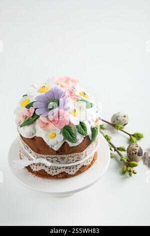 Torta di Pasqua, pane dolce decorato con orecchie conigliette e fiori primaverili su sfondo rosa. Vista dall'alto. Foto Stock