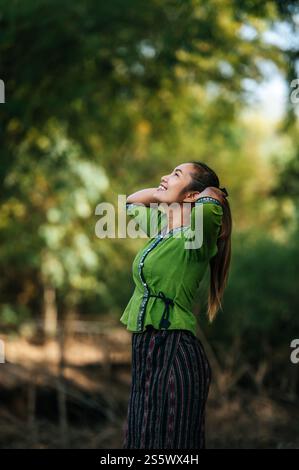 Ritratti la giovane donna asiatica che indossa bellissimi panni sorridente mentre si rilassa in campagna in thailandia, copia spazio Foto Stock