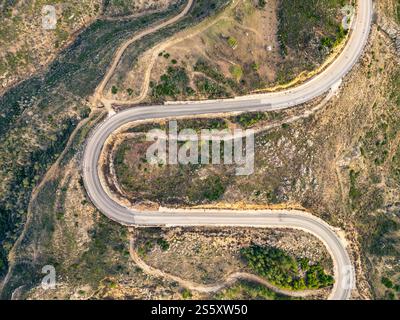 Una tortuosa strada asfaltata che attraversa zone con pochi alberi in autunno. Un'autostrada curva a S. Foto Stock