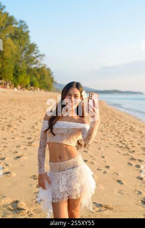 Happy Young Woman che prende Selfie con il concetto di sfondo Ocean Sunset Foto Stock