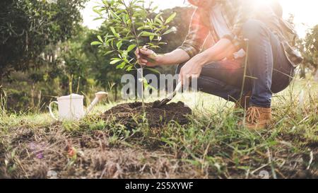 giardiniere giovane uomo, piantando albero in giardino, giardinaggio e annaffiatura piante. Foto Stock