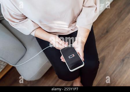 Donna che ricarica la batteria del telefono cellulare con batteria scarica. Collegare un caricabatterie a uno smartphone con un caricabatterie power Bank moderno Foto Stock