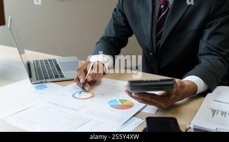 Commercialista che analizza i grafici di investimento fattura e premendo i pulsanti della calcolatrice sui documenti. Contabile contabile impiegato consulente bancario Foto Stock