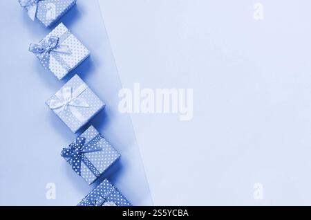 Piccole confezioni regalo di diversi colori con nastri si trovano su uno sfondo fantoccio di colore blu classico. Piccole confezioni regalo di diversi colori con nastri Foto Stock