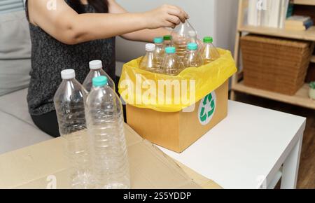 Casa ricicla donna eco-verde zero concept che lancia bottiglie di plastica vuote in un cestino con sacchetti per rifiuti gialli a casa Foto Stock