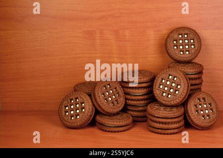 Panino al cioccolato, biscotti rotondi con ripieno di crema alla vaniglia su un tavolo di legno marrone con copyspace. Natura morta di biscotti dolci e gustosi con bianco Foto Stock