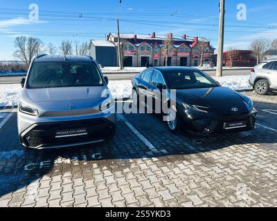 Kiev, Ucraina - 14 gennaio 2025: Un minivan Toyota argento e una berlina nera sono parcheggiati in una strada asfaltata sotto un cielo soleggiato durante l'inverno. Segno visibile Foto Stock