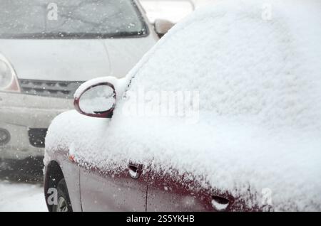 Frammenti di auto parcheggiate ricoperte di neve bianca. Frammenti di auto parcheggiate ricoperte di neve Foto Stock