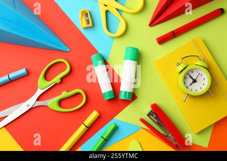 Composizione piatta con colla, forbici e altri articoli di cancelleria su sfondo colorato Foto Stock