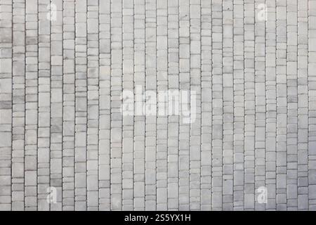 Lastre di pavimentazione di colore grigio sul marciapiede della strada pedonale. Schema grezzo di ciottoli con molte pietre di forma quadrata in primo piano. Lastre di pavimentazione di colore grigio Foto Stock