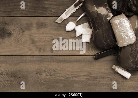Roba di spacciatori. Molte grandi confezioni di polvere di eroina e articoli per l'uso di narcotici su un tavolo di legno. Trug business and trafficking concept. Farmaco Foto Stock