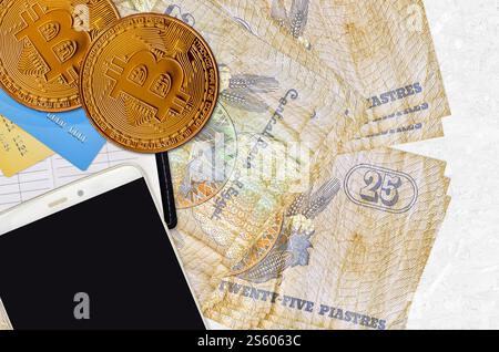 25 carte egiziane e monete d'oro con smartphone e carte di credito. Concetto di investimento in criptovaluta. Crypto minerario o transplacti di commercio Foto Stock