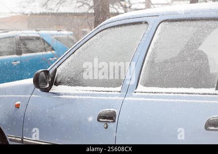 Frammenti di auto parcheggiate ricoperte di neve bianca. Frammenti di auto parcheggiate ricoperte di neve Foto Stock