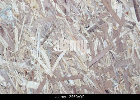 Pannelli OSB realizzati con trucioli di legno marrone levigati su uno sfondo di legno. Vista dall'alto dello sfondo con inserti in legno OSB, superfici strette. Pannelli OSB di colore marrone Foto Stock