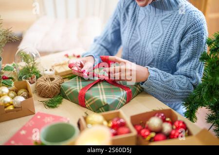 Donna in maglione a maglia che avvolge i regali di natale con carta ecologica da ragazza che confeziona i regali di natale concetto natalizio. Foto Stock