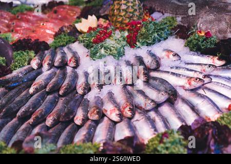 Pesce fresco assortito, tra cui pesce e crostacei esposti sul ghiaccio con verdure ed elementi decorativi in un mercato locale Foto Stock