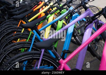 Una vivace collezione di biciclette con cornici colorate parcheggiate vicino all'esterno alla luce del sole che creano una scena vivace Foto Stock