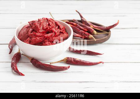 Pasta tradizionale di peperoncino turco in ciotola o cucchiaio con peperoni secchi su tavola di legno, cibo sano fatto in casa Foto Stock