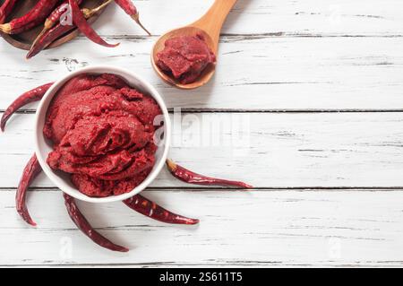 Pasta tradizionale di peperoncino turco in ciotola o cucchiaio con peperoni secchi su tavola di legno, cibo sano fatto in casa Foto Stock