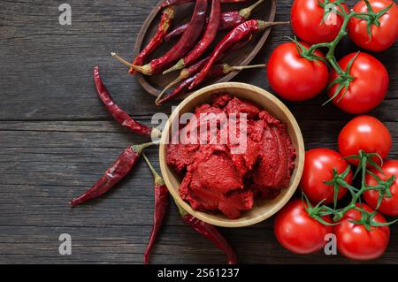 Peperoncino turco tradizionale e pasta di pomodoro nel recipiente o cucchiaio con peperoni secchi e pomodori freschi in tavola Foto Stock