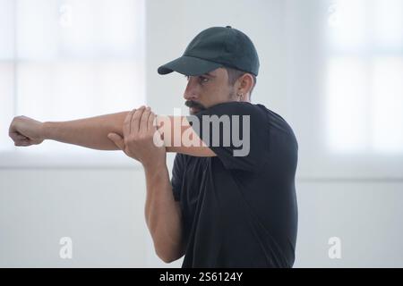 Riscaldati. Uomo muscoloso che si allunga braccia e spalle prima di allenarsi in palestra. Foto Stock