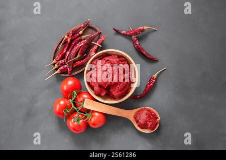 Peperoncino turco tradizionale e pasta di pomodoro nel recipiente o cucchiaio con peperoni secchi e pomodori freschi in tavola Foto Stock