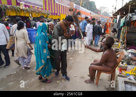 Kolkata, Bengala Occidentale, India. 12 gennaio 2025. Il campo di transito di Gangasagar Mela risuona con la vita mentre i pellegrini e i sadhus iniziano il loro viaggio verso l'isola Sagar. I vivaci autobus li trasportano prima al lotto 8, seguiti da navi e autobus per l'isola sacra, a 117 km da Kolkata. L'annuale festival indù, che segna Makar Sankranti il 14 gennaio 2025, attrae migliaia di persone in cerca di un tuffo sacro alla confluenza del Gange e del Golfo del Bengala. Ogni viaggiatore riflette devozione e fede mentre procede con fervore spirituale. Il governo e le ONG garantiscono servizi essenziali, promuovendo un'esperienza senza soluzione di continuità Foto Stock