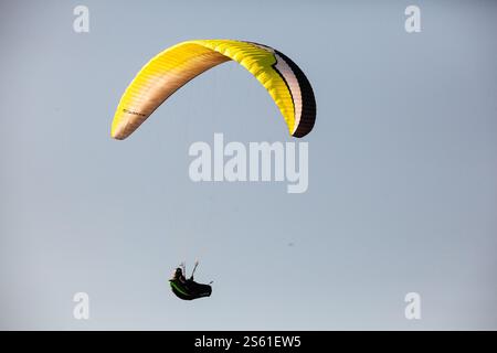 Parapendio in volo contro un cielo azzurro Foto Stock