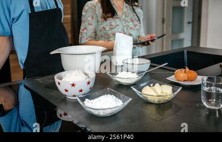 Madre e figlio irriconoscibili che preparano gli ingredienti seguendo la ricetta online su tablet Foto Stock
