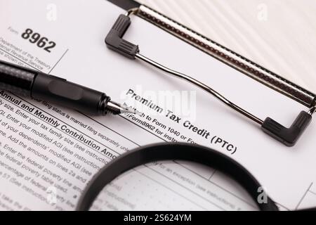 IRS Form 8962 Premium tax Cerdit PTC vuoto su tablet A4 si trova sul tavolo dell'ufficio con penna e lente di ingrandimento da vicino. Modulo IRS 8962 certificato fiscale premium Foto Stock