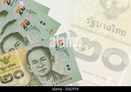 20 banconote thailandesi in Baht sono impilate sullo sfondo di grandi banconote semitrasparenti. Sfondo aziendale astratto con spazio di copia. 20 bollette thailandesi Foto Stock