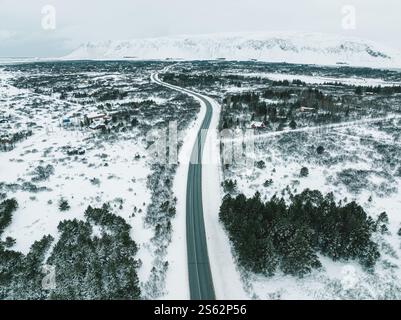 Vista aerea di una strada innevata che si snoda attraverso un paesaggio invernale nel sud dell'Islanda. Foto Stock