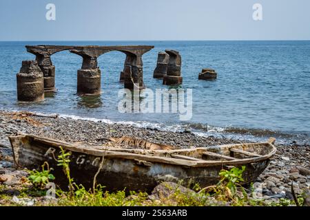 Resti di un vecchio molo coloniale del porto e di una vecchia barca da pesca a Sao Tome. Foto Stock
