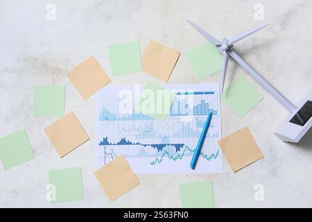 Diagrammi con note adesive vuote e modello di turbina eolica su sfondo chiaro. Concetto di energia verde Foto Stock