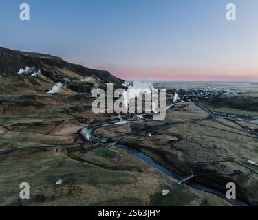 Veduta aerea di Hveragerdi, Islanda meridionale, con sfiati geotermici a vapore e paesaggi aspri all'alba. Foto Stock